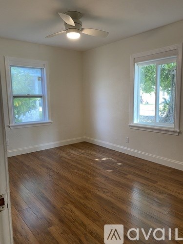 A room with wooden floors and two windows.