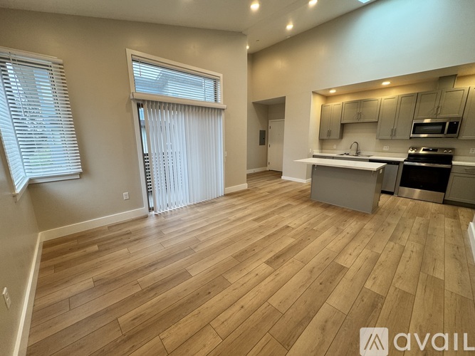 A spacious kitchen with wooden flooring and a dining area with a table and chairs.