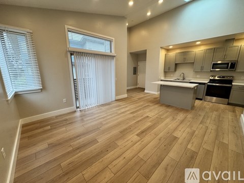 A spacious kitchen with wooden flooring and a dining area with a table and chairs.