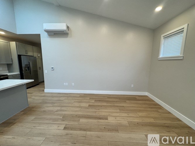 A room with wooden flooring and a window with blinds.