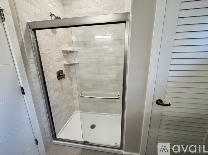 A shower stall with a glass door and a white door to the right.
