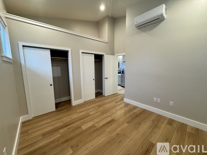 A room with wooden floors and three doors.