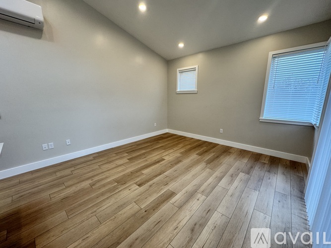 A room with wooden flooring and a window with blinds.