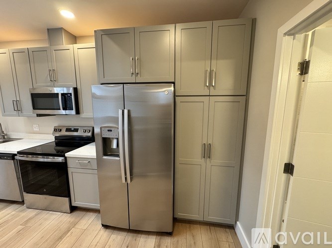 A kitchen with a refrigerator, microwave, oven, and cabinets.
