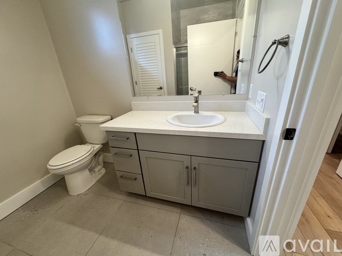 A bathroom with a toilet, sink, and mirror.