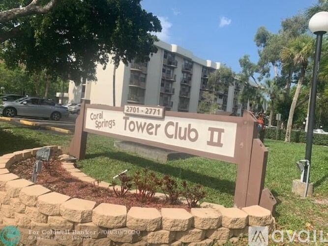 A sign for Coral Springs Tower Club II in front of a building.