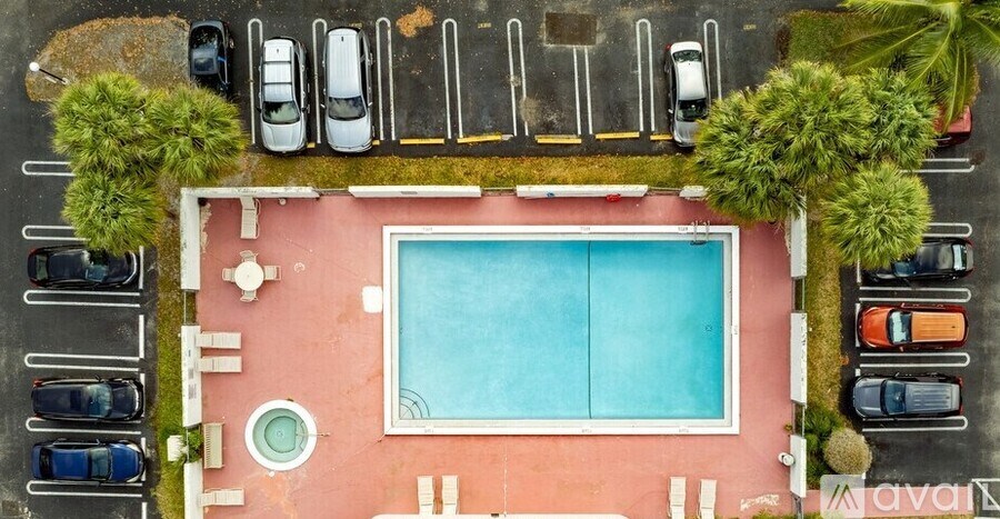 An aerial view of a pool surrounded by cars and trees.