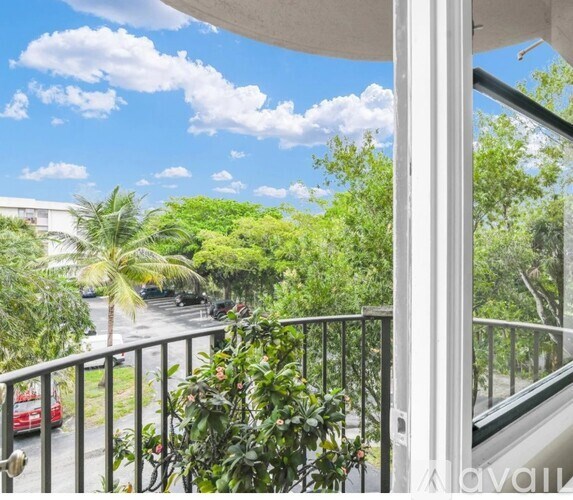 A balcony view with a red car and greenery.