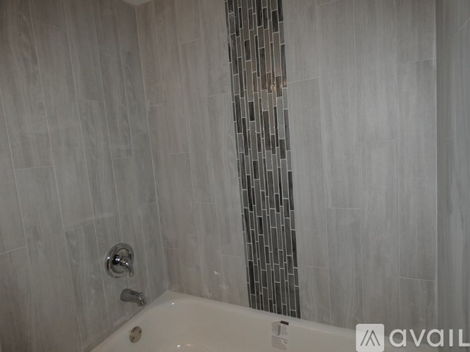 A white bathtub with a silver faucet and a wall of tiles.
