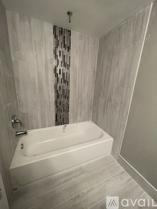 A white bathtub in a bathroom with a glass block wall.