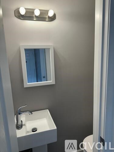 A white sink under a mirror with lights above it.