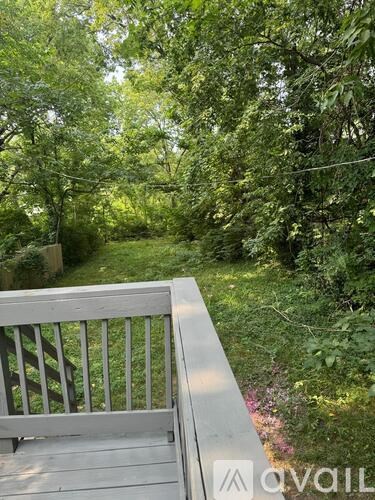A wooden bench sits on a deck overlooking a lush green forest.