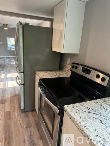 A kitchen with a refrigerator, oven, and stove top.