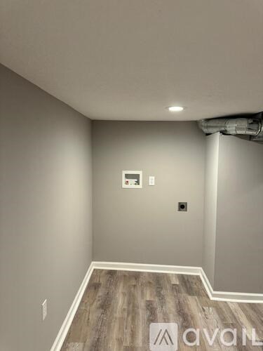 A room with wooden flooring and a wall-mounted electrical switch.