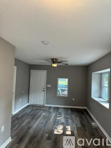 A room with a ceiling fan and wooden flooring.