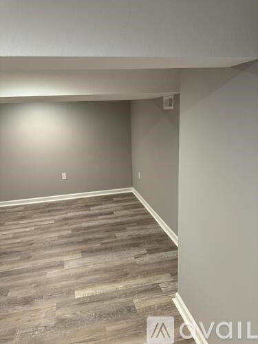 A room with wooden flooring and a wall socket.