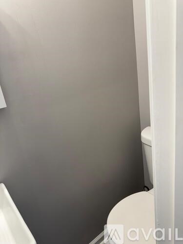 A white toilet in a bathroom with grey walls.