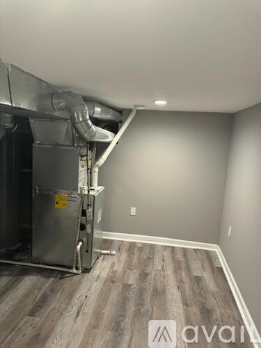 A room with a wood floor and a wall-mounted heating unit.