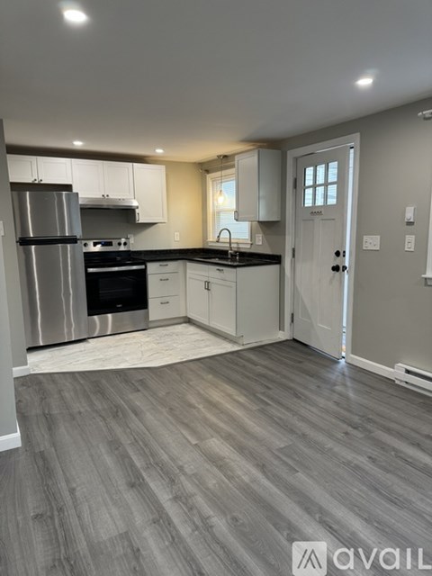 A kitchen with a stainless steel refrigerator and wooden flooring.