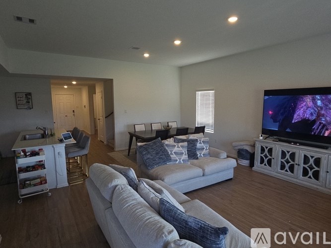 A living room with a white couch and a television on a cabinet.
