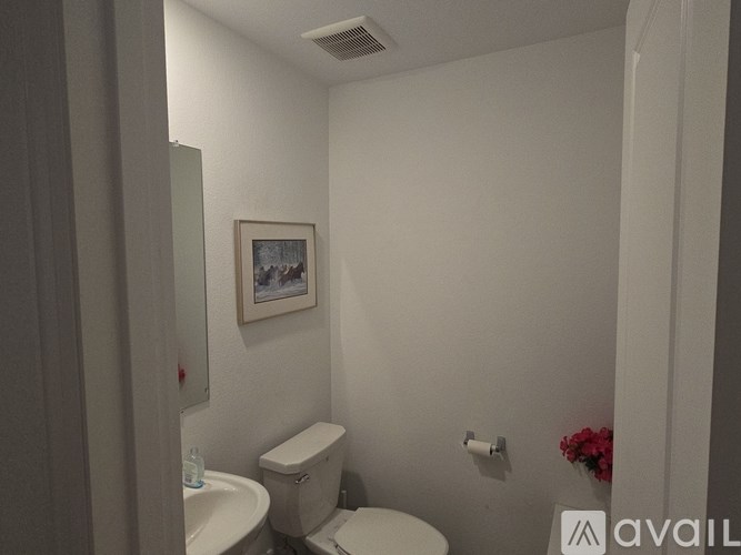 A bathroom with a toilet, sink, and a picture on the wall.