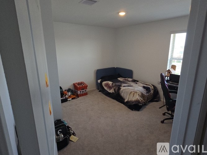 A dog is sleeping on a bed in a room with a suitcase and a box on the floor.