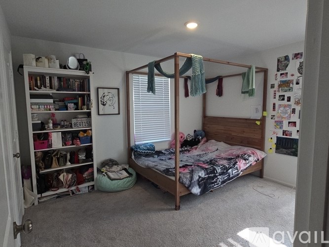A bedroom with a bed, a bookcase, and a window with curtains.