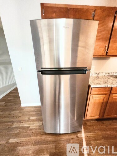 A stainless steel fridge with a black handle sits in a kitchen.