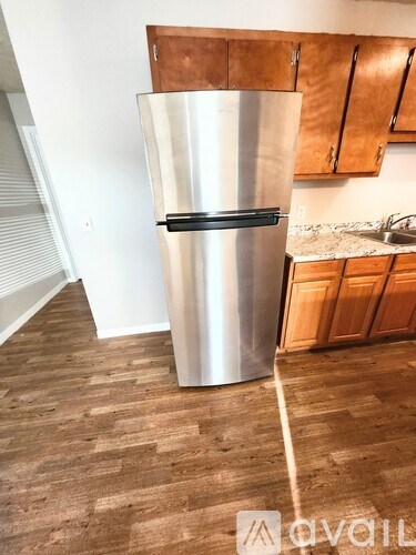 A stainless steel refrigerator in a kitchen with wooden flooring.