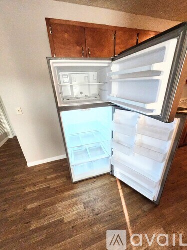 A white refrigerator with its door open in a room with wooden flooring.