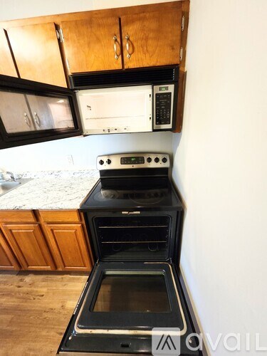 A kitchen with a black oven and wooden cabinets.