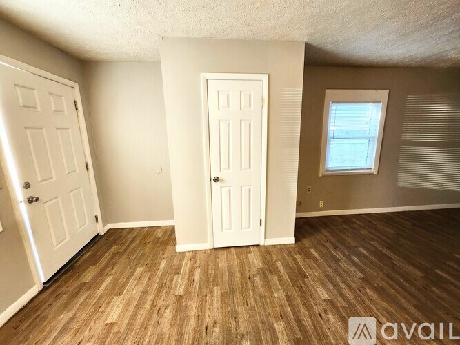 A room with two doors and a window with blinds.