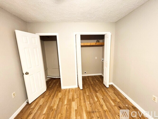 A room with two open doors and wooden flooring.