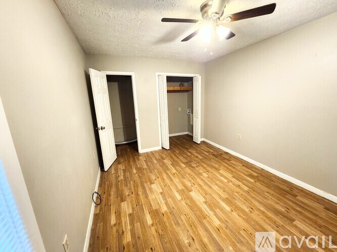 A room with a ceiling fan and wooden flooring.