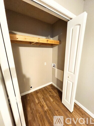 A small room with a white door and wooden flooring.