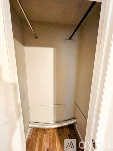 A small, empty room with wooden flooring and white walls.