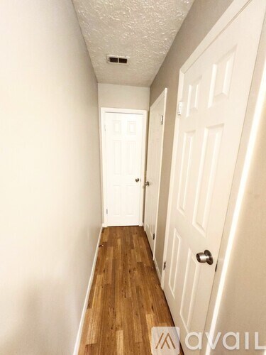 A hallway with white doors and wooden floors.