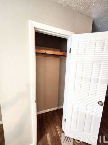 A white door is open to a small room with a wooden floor.
