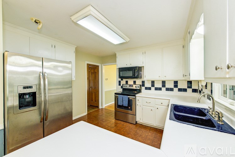 A kitchen with a refrigerator, microwave, oven, sink, and cabinets.