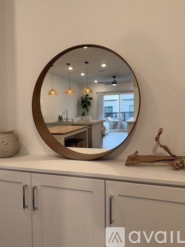 A round mirror is mounted on a wall above a cabinet.