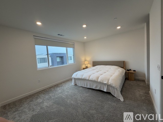 A bedroom with a large bed and a window overlooking a building.