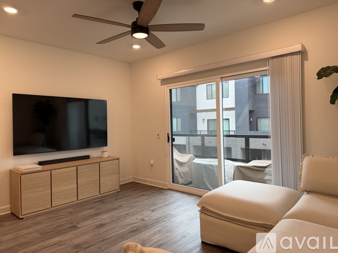 A living room with a television, a white sofa, and a ceiling fan.