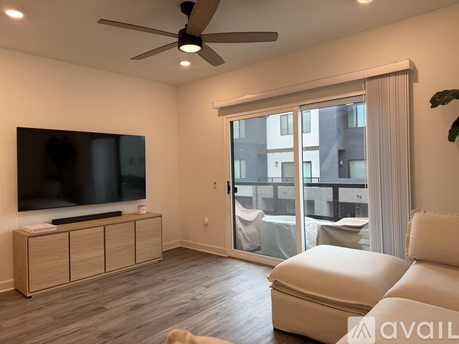 A living room with a television, a white sofa, and a ceiling fan.