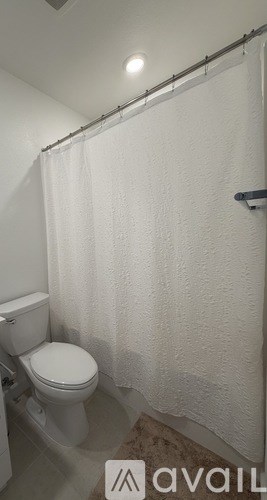 A white toilet in a small bathroom with a shower curtain.