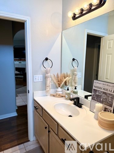 A bathroom with a sink, mirror, and a light on the wall.