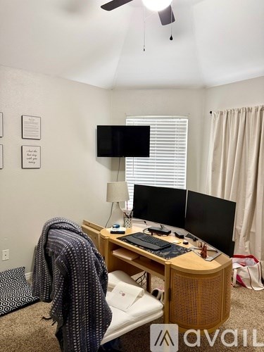 A room with a desk, a bed, and a ceiling fan.