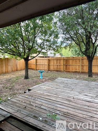 A wooden deck with a teal bird bath in the middle of a backyard.