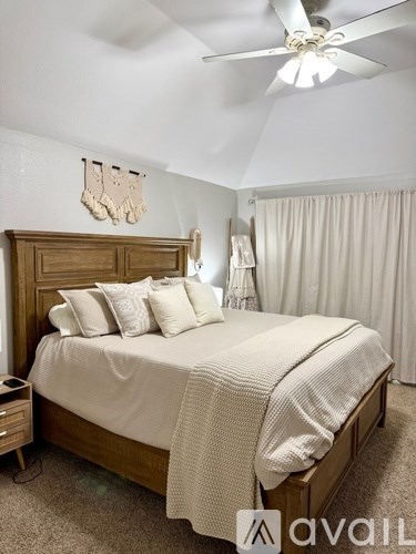 A bedroom with a large bed and a ceiling fan.