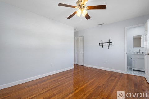 A room with a ceiling fan and wooden floors.
