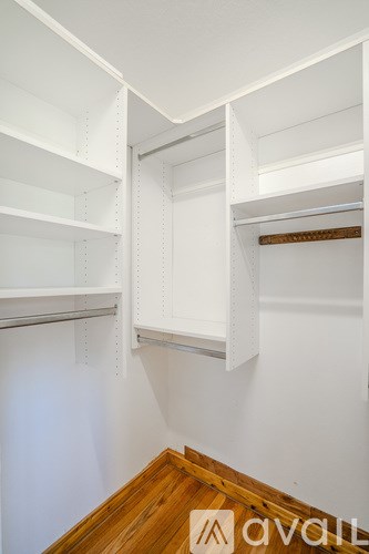 A white closet with shelves and a wooden floor.
